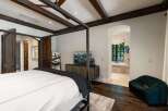Experience luxurious living in this master suite featuring a grand four-poster bed and exposed wooden beams.