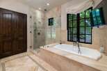 Indulge in luxury with this stunning bathroom featuring a spacious glass-enclosed shower and a deep soaking tub.