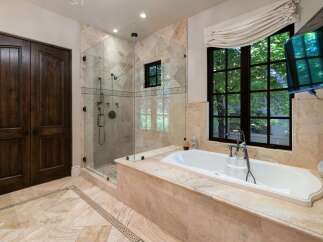 Indulge in luxury with this stunning bathroom featuring a spacious glass-enclosed shower and a deep soaking tub.