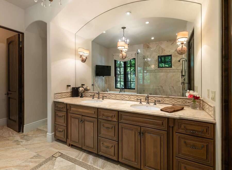 Indulge in luxury with this stunning master bathroom featuring a spacious double vanity with rich wooden cabinetry and elegant marble countertops.