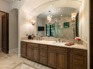 Indulge in luxury with this stunning master bathroom featuring a spacious double vanity with rich wooden cabinetry and elegant marble countertops.