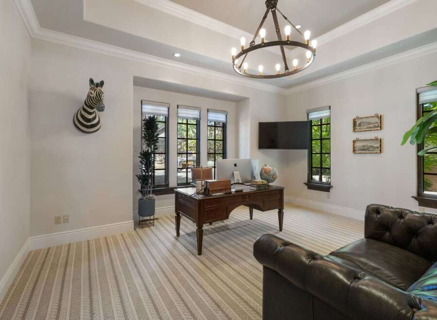 This executive office features a large wooden desk with a computer and globe, perfect for productivity.