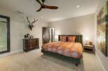 This master bedroom offers a luxurious retreat with a plush green upholstered bed adorned with vibrant orange patterned bedding.