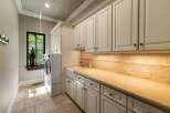 This laundry room boasts ample storage with custom cream-colored cabinetry, both above and below the countertop.