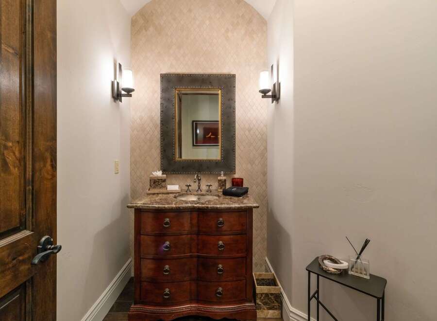 Discover this elegant powder room featuring a charming vanity with a marble countertop and ornate wooden drawers.
