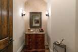 Discover this elegant powder room featuring a charming vanity with a marble countertop and ornate wooden drawers.