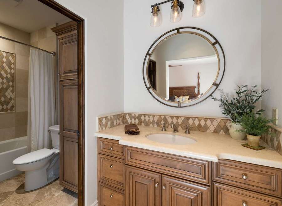 This beautifully appointed bathroom features a spacious vanity with ample storage and a decorative tile backsplash.
