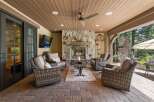 Experience ultimate outdoor living with this covered patio, featuring a cozy stone fireplace and comfortable wicker seating.