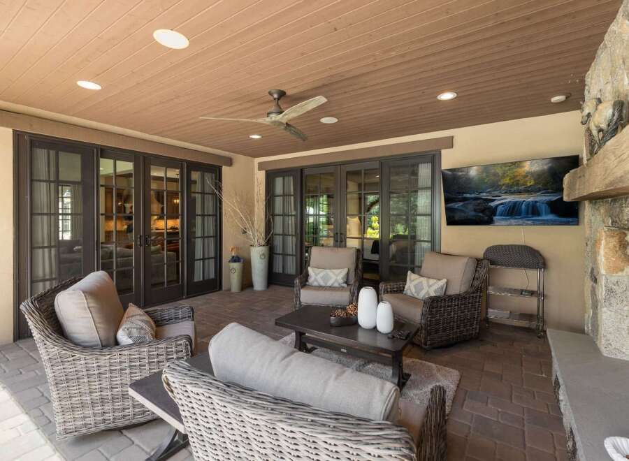 Enjoy outdoor living at its finest on this covered patio, complete with a cozy seating area and a large flat-screen TV perfect for entertaining.