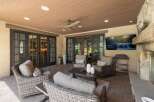 Enjoy outdoor living at its finest on this covered patio, complete with a cozy seating area and a large flat-screen TV perfect for entertaining.