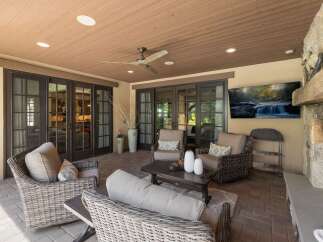 Enjoy outdoor living at its finest on this covered patio, complete with a cozy seating area and a large flat-screen TV perfect for entertaining.