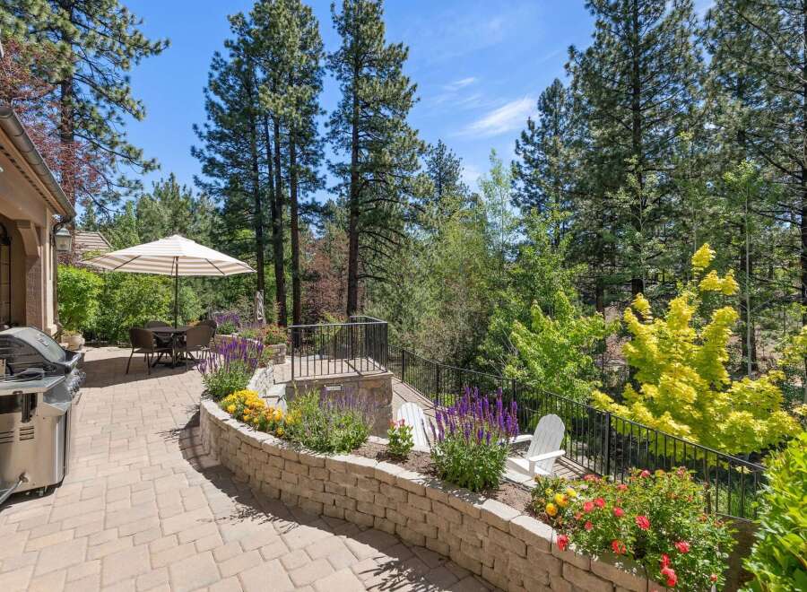 Enjoy outdoor living at its finest on this spacious patio, complete with a built-in grill and a dining set under a striped umbrella.