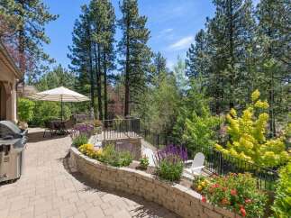 Enjoy outdoor living at its finest on this spacious patio, complete with a built-in grill and a dining set under a striped umbrella.