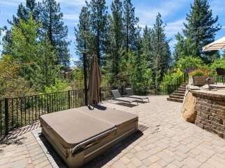 Enjoy outdoor living at its finest with this spacious patio featuring a covered hot tub and two comfortable lounge chairs, perfect for relaxation.