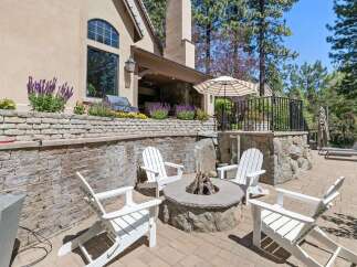 Enjoy outdoor living at its finest with this beautifully designed patio featuring a stone fire pit and comfortable Adirondack chairs, perfect for gathering with friends and family.