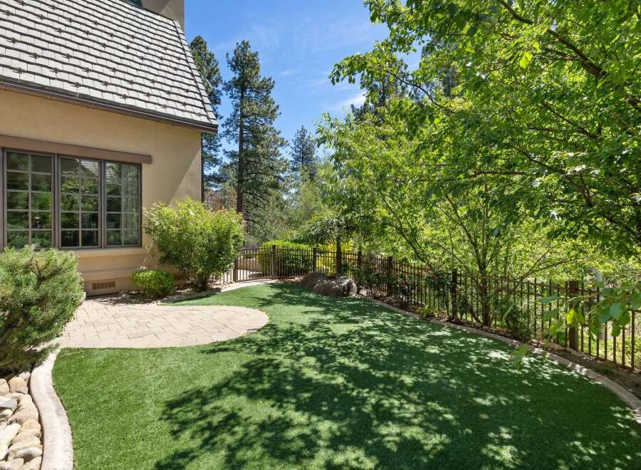 Enjoy outdoor living in this beautifully landscaped backyard featuring a lush green lawn and a charming stone patio.