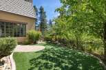 Enjoy outdoor living in this beautifully landscaped backyard featuring a lush green lawn and a charming stone patio.