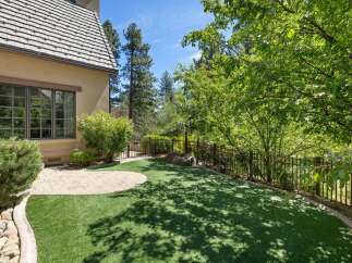 Enjoy outdoor living in this beautifully landscaped backyard featuring a lush green lawn and a charming stone patio.