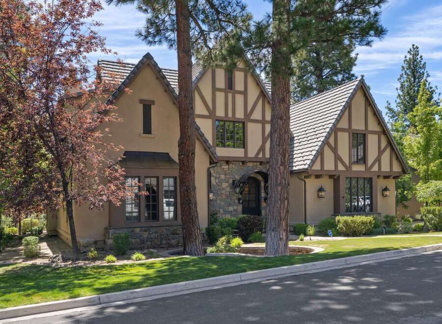 Discover this charming Tudor-style home featuring a striking stone entryway and intricate half-timbered accents.