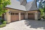 This stunning property features a spacious three-car garage with elegant wooden doors and decorative windows, perfect for housing multiple vehicles.