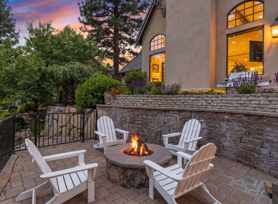 Experience outdoor living at its finest with this inviting patio featuring a stone fire pit and comfortable Adirondack chairs, perfect for gathering with loved ones.