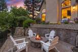 Experience outdoor living at its finest with this inviting patio featuring a stone fire pit and comfortable Adirondack chairs, perfect for gathering with loved ones.