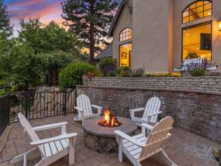 Experience outdoor living at its finest with this inviting patio featuring a stone fire pit and comfortable Adirondack chairs, perfect for gathering with loved ones.