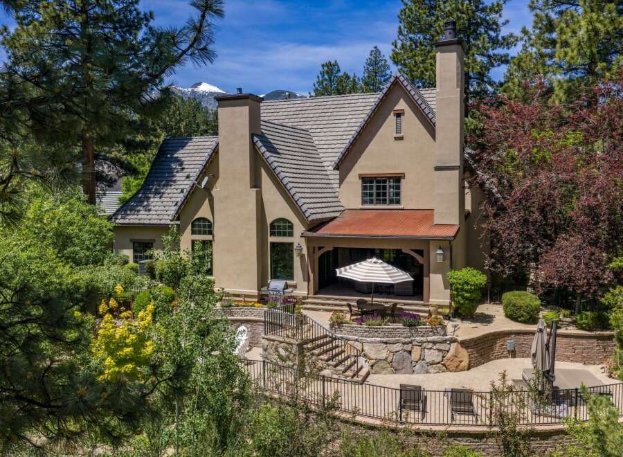 Experience luxurious mountain living in this stunning home, featuring a covered patio with an outdoor dining area perfect for entertaining.