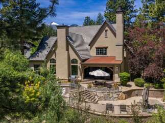 Experience luxurious mountain living in this stunning home, featuring a covered patio with an outdoor dining area perfect for entertaining.