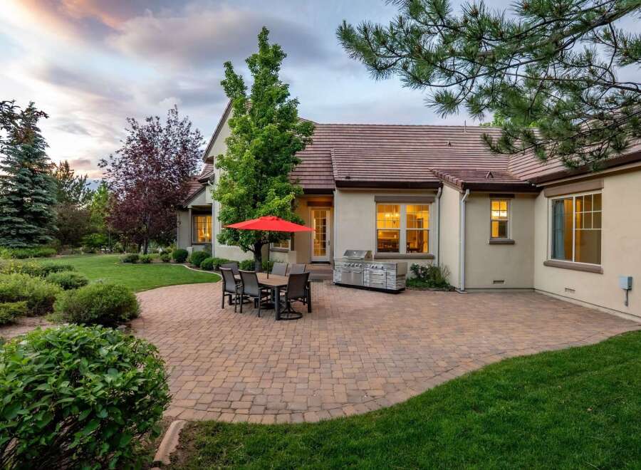 Enjoy outdoor living with this spacious patio featuring a dining set and a built-in grill, perfect for entertaining.