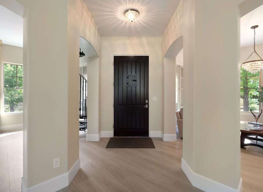 Step into this elegant entryway featuring a grand dark wood front door, illuminated by a stunning crystal ceiling light.