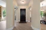 Step into this elegant entryway featuring a grand dark wood front door, illuminated by a stunning crystal ceiling light.