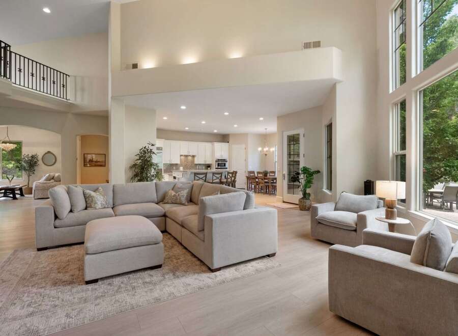 Experience luxurious open-concept living in this stunning home, featuring a grand living area with a sectional sofa and a large ottoman, perfect for entertaining.