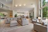 Experience luxurious open-concept living in this stunning home, featuring a grand living area with a sectional sofa and a large ottoman, perfect for entertaining.