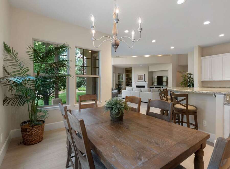 This spacious dining area features a large, rustic wooden table perfect for family gatherings, complemented by comfortable seating and a charming chandelier.