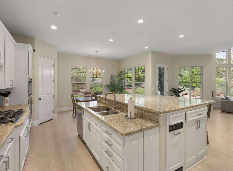 Experience the epitome of modern living in this stunning kitchen, featuring a spacious island with granite countertops and a double sink.