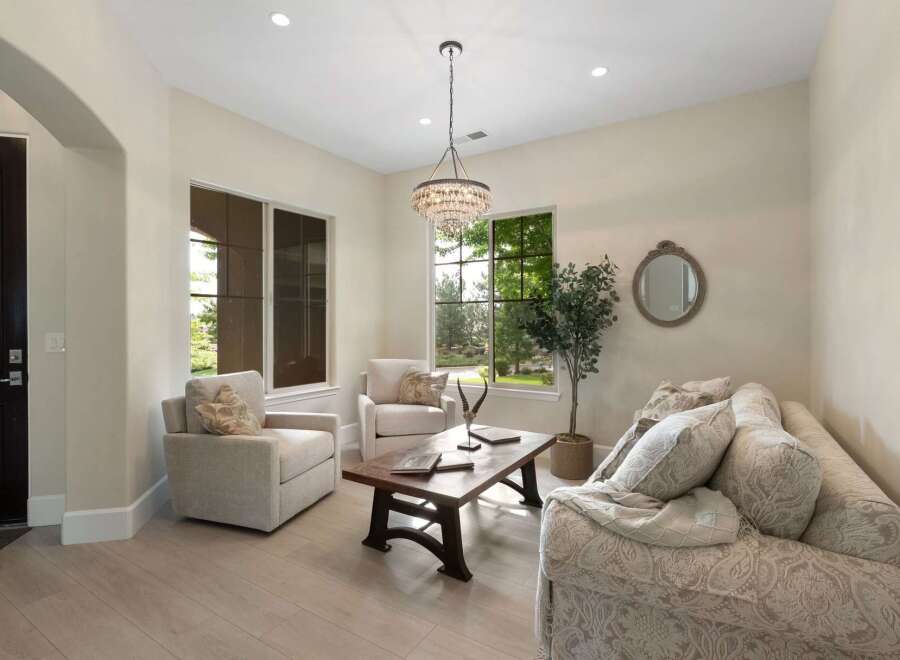 Step into this inviting living room, bathed in natural light from large windows overlooking lush greenery.