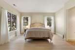 This serene bedroom features a plush king-sized bed with a stylish upholstered headboard, perfect for restful nights.