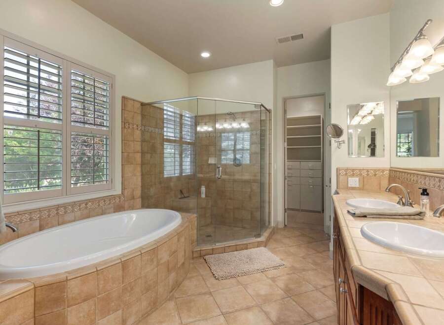 Indulge in luxury with this stunning bathroom featuring a spacious soaking tub and a separate glass-enclosed shower.