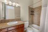 This bathroom features a spacious vanity with a white oval sink and a tiled countertop, complemented by a large mirror with a vanity light fixture above.