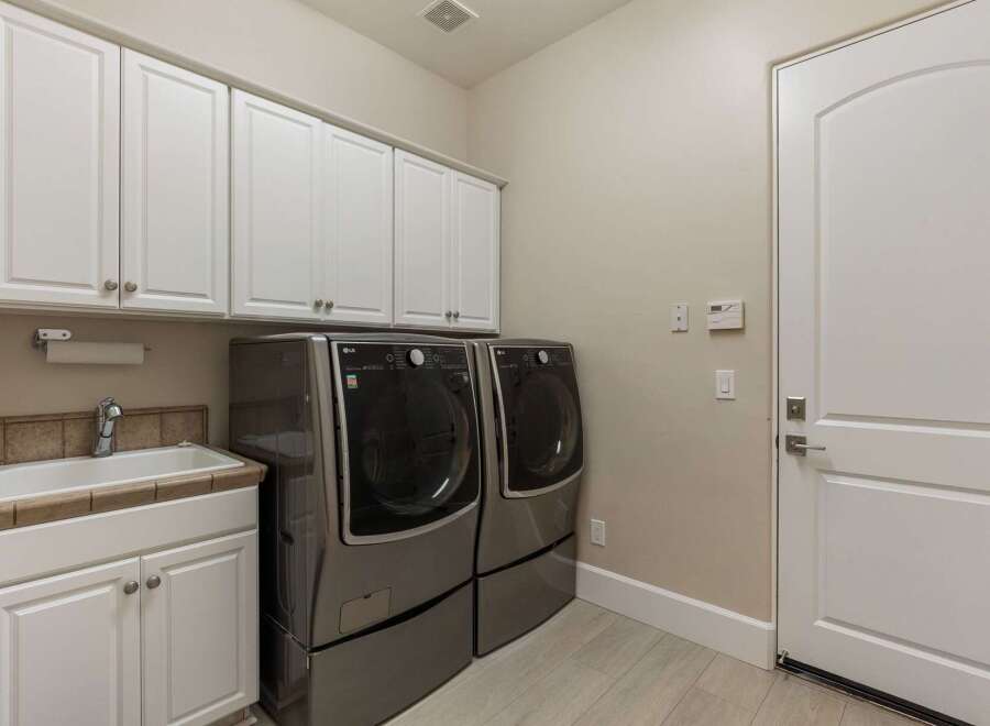 This spacious laundry room features a large utility sink and ample cabinet storage, perfect for organizing your household essentials.