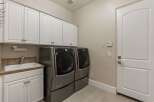 This spacious laundry room features a large utility sink and ample cabinet storage, perfect for organizing your household essentials.