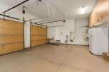 This spacious garage offers ample storage with overhead cabinets and a convenient workbench area.