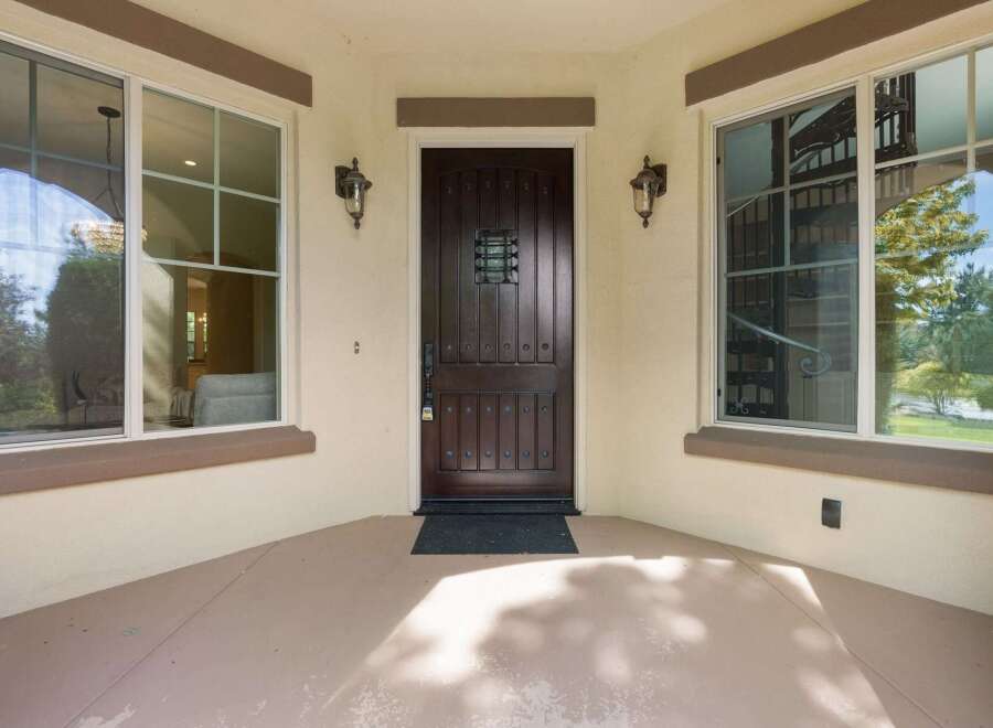 Step into elegance with this stunning dark wood front door, featuring intricate detailing and a decorative glass insert for a touch of sophistication.