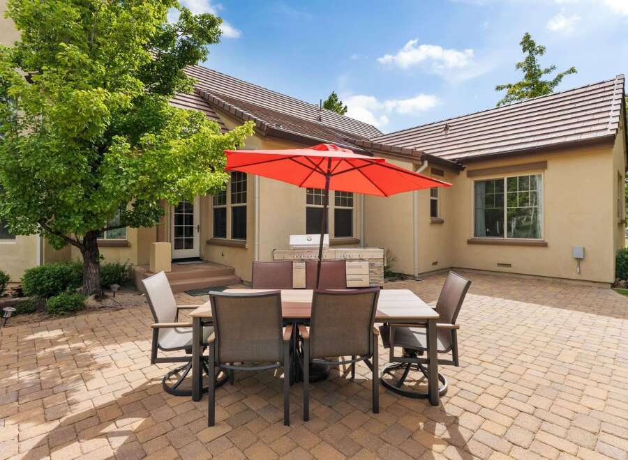 Enjoy outdoor living with this spacious patio featuring a dining set and a built-in grill, perfect for entertaining.