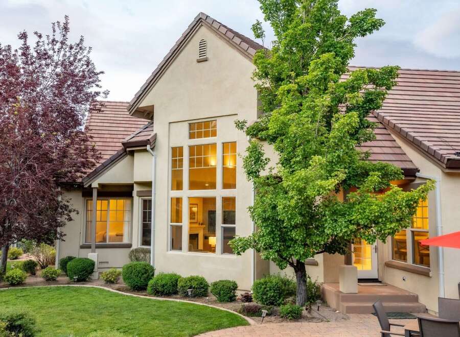 This stunning home features a grand facade with a towering multi-pane window that illuminates the interior with a warm glow.