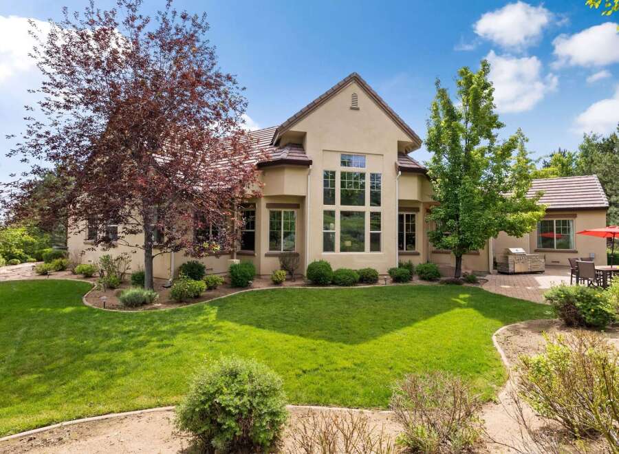 This stunning home boasts a beautifully landscaped yard with mature trees and a lush green lawn, perfect for outdoor enjoyment.