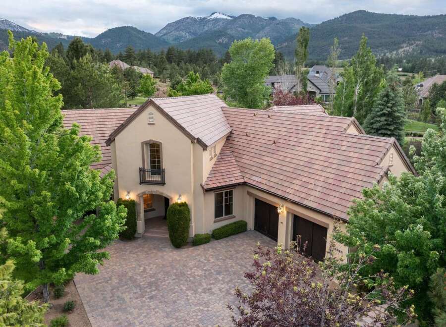 Experience luxury living in this stunning mountain-view estate, featuring a grand entrance with arched doorways and elegant exterior lighting.