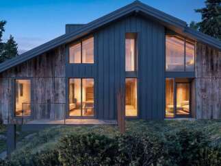 Experience modern mountain living in this stunning architectural home, featuring a striking blend of dark metal siding and rustic wood accents.