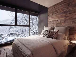 Experience cozy luxury in this mountain retreat bedroom, featuring a plush bed adorned with decorative pillows and a stunning panoramic window showcasing a serene winter landscape.